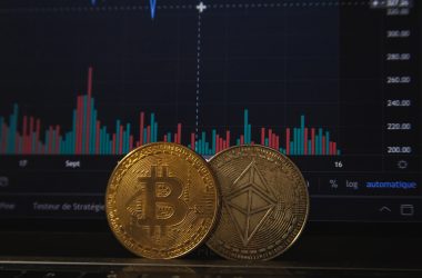 Featured image for bitcoin price decline story showing two bitcoins placed near a screen