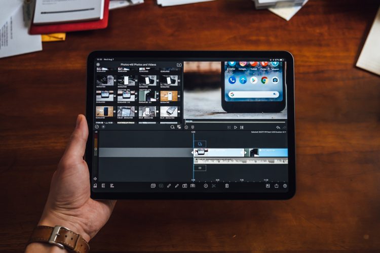 A person holding an iPad Pro while editing a video on it
